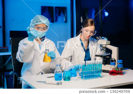 Young scientists conducting research investigations in a medical laboratory, a researcher in the foreground is using a microscope in laboratory Young scientists conducting research investigations in a medical laboratory, a researcher in the foreground is using a microscope in laboratory 130240709
