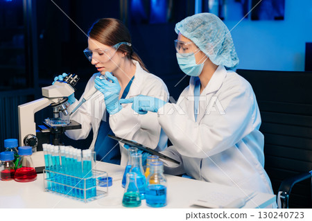 Modern Medical Research Laboratory Portrait of Two Scientists Working, Using Digital Tablet, Analyzing Samples, Talking. Modern Medical Research Laboratory Portrait of Two Scientists Working, Using Digital Tablet, Analyzing Samples, Talking. 130240723