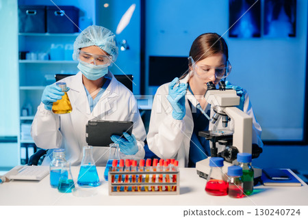 Modern Medical Research Laboratory Portrait of Two Scientists Working, Using Digital Tablet, Analyzing Samples, Talking. 130240724