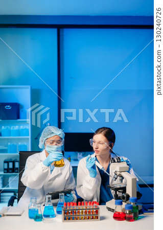 Modern Medical Research Laboratory Portrait of Two Scientists Working, Using Digital Tablet, Analyzing Samples, Talking. 130240726