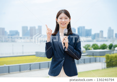 Businesswoman holding a microphone and pointing Businesswoman holding a microphone and pointing 130240794
