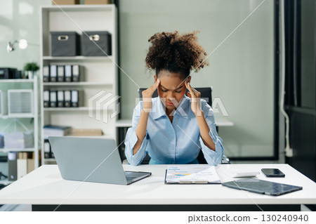 Woman feeling migraine head strain.Overworked businesswoman financier while working on laptop and tablet 130240940