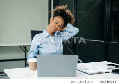 Overworked young Asian businesswoman office worker suffering from neck pain after had a long day at her office desk 130240944