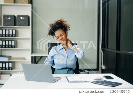 Overworked young Asian businesswoman office worker suffering from neck pain after had a long day at her office desk 130240945