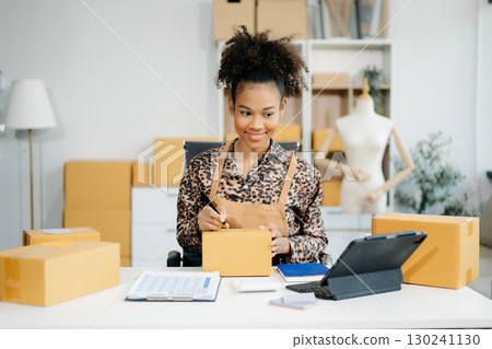Asian young woman SME working using smartphone or tablet taking receive and checking online purchase shopping order 130241130