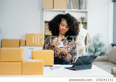 Asian young woman SME working using smartphone or tablet taking receive and checking online purchase shopping order 130241131