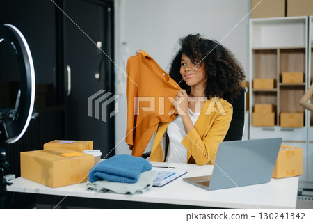 Beautiful lady blogger showing clothes in front of the camera to recording vlog video live streaming at her shop 130241342