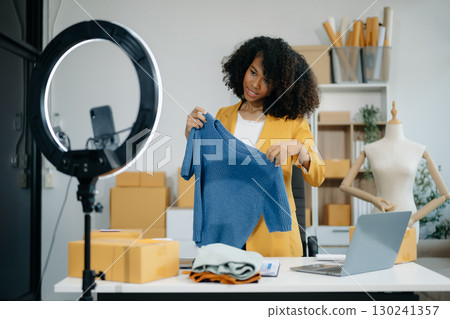 Beautiful lady blogger showing clothes in front of the camera to recording vlog video live streaming at her shop Beautiful lady blogger showing clothes in front of the camera to recording vlog video live streaming at her shop 130241357