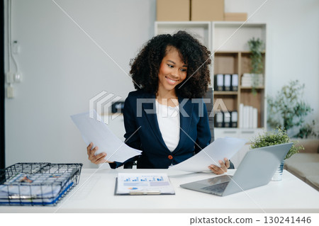 Confident woman with a smile standing holding notepad and tablet Confident woman with a smile standing holding notepad and tablet 130241446