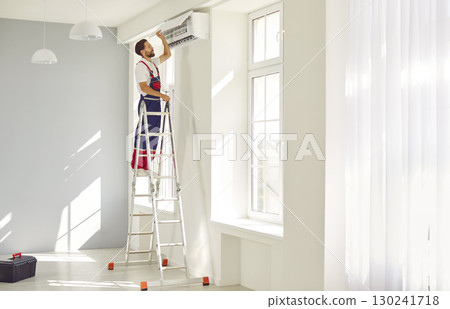 Portrait of professional electrician man maintaining air conditioner indoors. 130241718