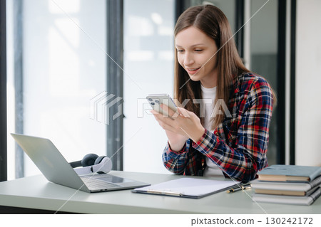 Confident woman with a smile standing holding notepad and tablet at the office. 130242172