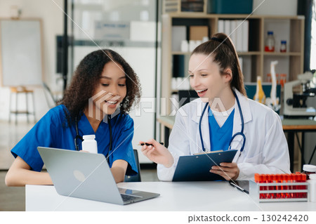 Doctor Talks With Professional Head Nurse or Surgeon, They Use Digital tablet Computer. Diverse Team of Health Care Specialists Discussing Test Result 130242420