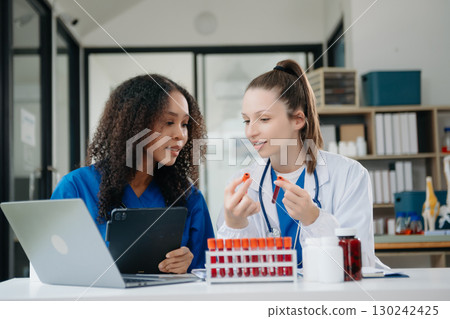 Doctor Talks With Professional Head Nurse or Surgeon, They Use Digital tablet Computer. Diverse Team of Health Care Specialists Discussing Test Result 130242425