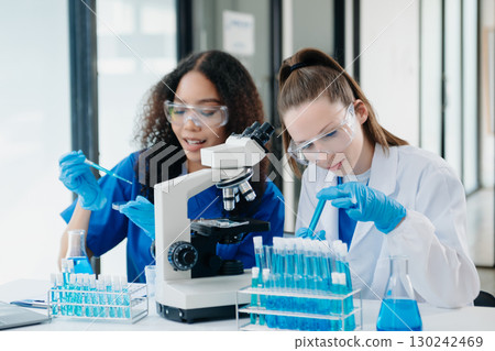 Modern Medical Research Laboratory Portrait of Two African American Scientists Working, Using Digital Tablet, Analyzing Samples, Talking. 130242469