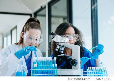 Modern Medical Research Laboratory Portrait of Two African American Scientists Working, Using Digital Tablet, Analyzing Samples, Talking. 130242470