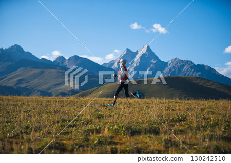 Fitness woman trail runner running in grassland with snow capped mountains in the background Fitness woman trail runner running in grassland with snow capped mountains in the background 130242510