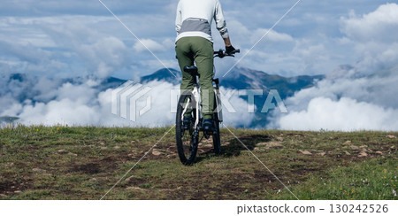 Asian woman riding a mountain bike down hill on beautiful mountain top 130242526