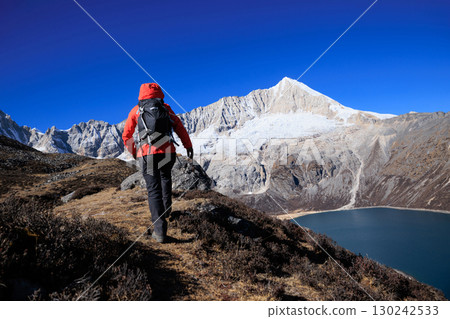 Backpacking woman hiking on high altitude mountain top 130242533