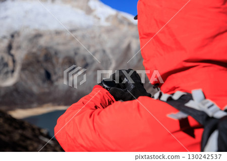 Backpacking woman set the sports watch on high altitude mountain top 130242537
