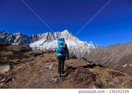 Backpacking woman hiking on high altitude mountain top 130242539