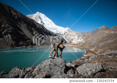 Backpacking woman hiking on high altitude mountain top 130242554
