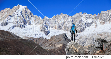 Backpacking woman hiking on high altitude mountain top 130242565