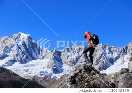 Backpacking woman hiking on high altitude mountain top 130242569