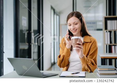 Confident woman with a smile standing holding notepad and tablet at the office. 130242742