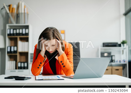 Frustrated young businesswoman working on a laptop computer sitting at his working place 130243094