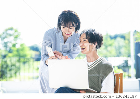 A couple searching on a computer and smartphone A couple searching on a computer and smartphone 130243187