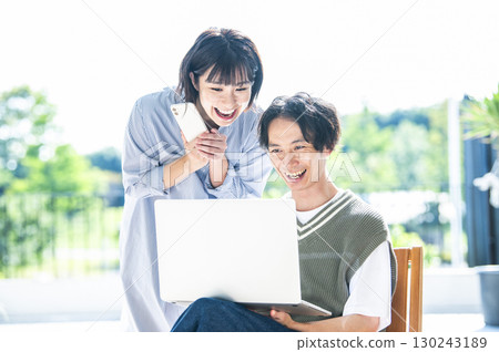 A couple searching on a computer and smartphone 130243189