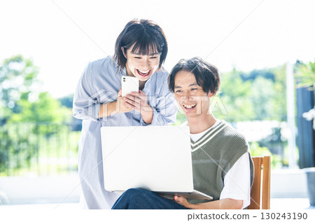 A couple searching on a computer and smartphone A couple searching on a computer and smartphone 130243190