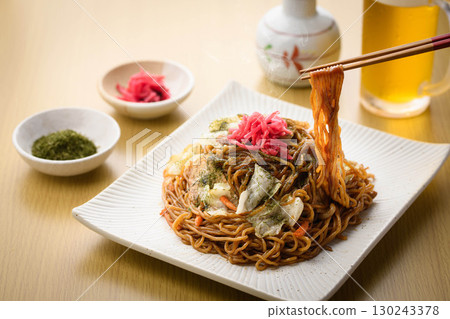 新鮮出爐的熱騰騰的炒麵配上醬汁和冰鎮啤酒——這是經典的居酒屋菜單,配有飲料。 新鮮出爐的熱騰騰的炒麵配上醬汁和冰鎮啤酒——這是經典的居酒屋菜單,配有飲料。 130243378