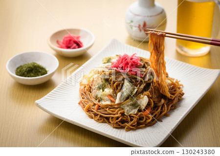 Freshly made piping hot yakisoba noodles with sauce and cold beer - a classic izakaya menu accompanied by a drink. 130243380