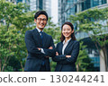 young japanese business people, a man and a woman, in office attire, standing in front of an office building 130244241