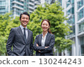 young japanese business people, a man and a woman, in office attire are smiling and looking at the camera 130244243