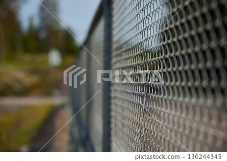 A Beautiful CloseUp of a ChainLink Fence Framed by a Lush Natural Background Setting 130244345