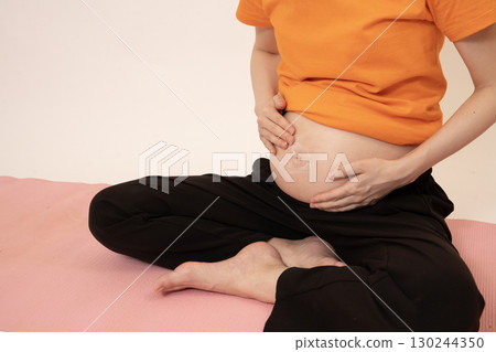 Woman applying cream to her 8-month pregnant belly 130244350