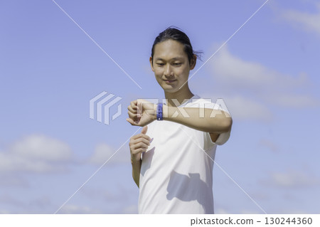 一名年輕男子在多摩川沿岸跑步時查看他的智慧手錶 一名年輕男子在多摩川沿岸跑步時查看他的智慧手錶 130244360