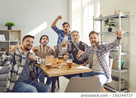 Group of excited friends watching football match on tv at home with beer and snacks. Group of excited friends watching football match on tv at home with beer and snacks. 130244737