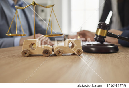 Toy cars that got in crash on table with gavel and justice scales with accident lawyer in background Toy cars that got in crash on table with gavel and justice scales with accident lawyer in background 130244739