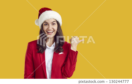 Happy woman advertises Christmas sale and points to copy space on yellow background 130244777