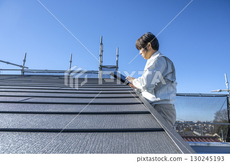 A man checking the progress of roof repair work on a detached house A man checking the progress of roof repair work on a detached house 130245193