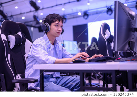 Back view of a male student immersed in a game in a gaming chair 130245374