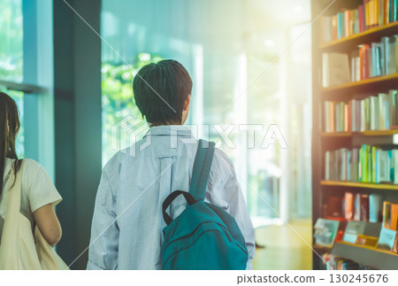 男女學生走過擺滿書架的圖書館 130245676