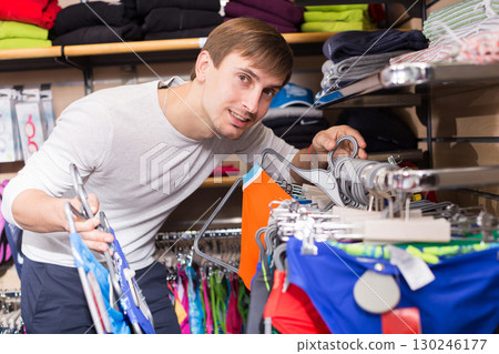 Young man shopping for swimwear in clothing store 130246177