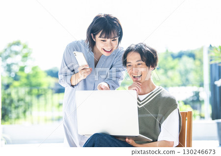 A couple searching on a computer and smartphone 130246673