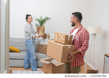 Homeownership Journey: A smiling young couple packs and unpacks boxes as they move into their new home, marking their journey of homeownership through a mortgage 130246766