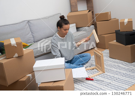 DIY Home Improvement: A close-up of a woman meticulously assembling a newly purchased wooden shelf in her warm living room, adding a personal touch to her space DIY Home Improvement: A close-up of a woman meticulously assembling a newly purchased wooden shelf in her warm living room, adding a personal touch to her space 130246771