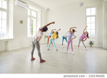 Woman choreographer showing her students girls stretching exercises in dance studio. 130246889